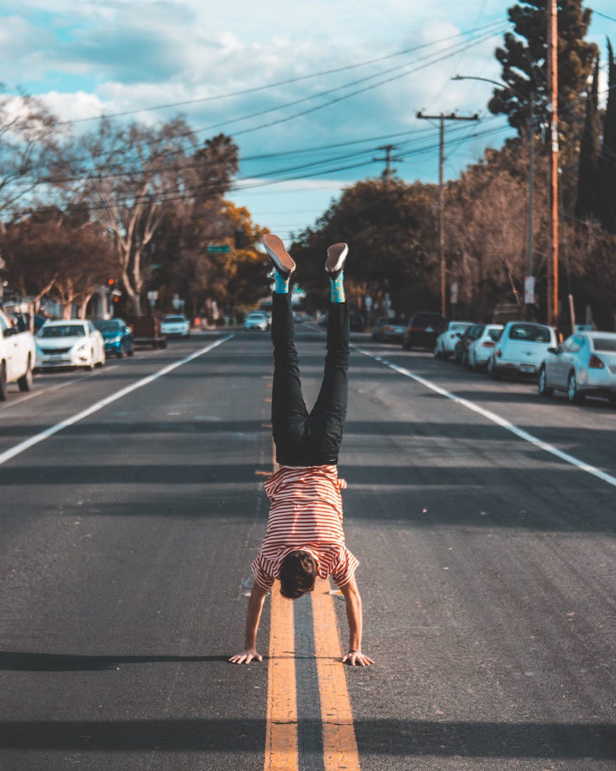 A man doing a handstand in the middle of the road