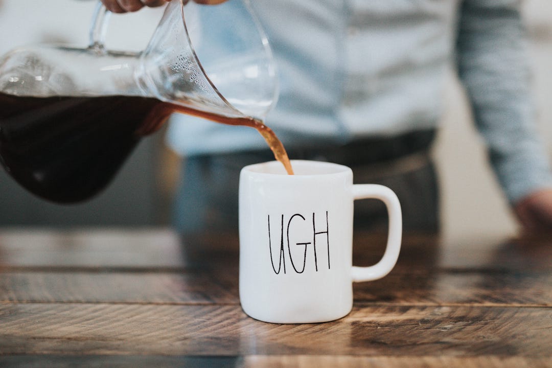 A coffee mug that says UGH